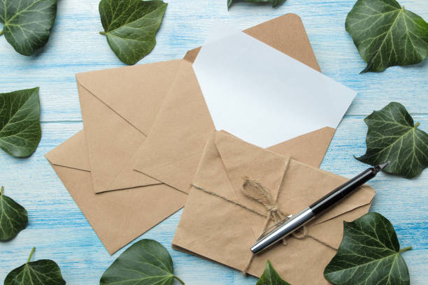 istock craft envelopes with a blank for text and green leaves on a blue wooden table. top view 1468061526