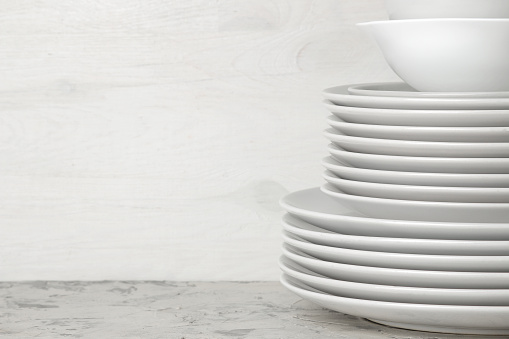 A stack of dishes. tableware on a light concrete background. dishes for serving the table. white plates and bowls in a stack. space for text