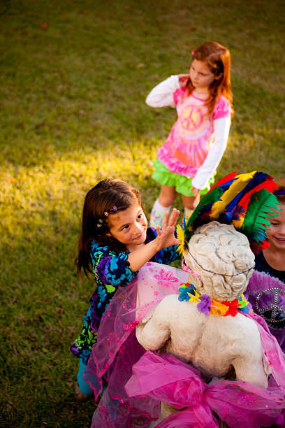 Young girl dresses up statue with sisters stock photo