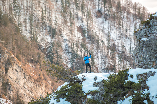Fit Caucasian trail runner standing alone and looking at winter nature landscape. Travel alone Europe tourism.