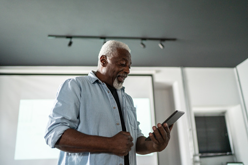 Senior man talking on digital tablet at work