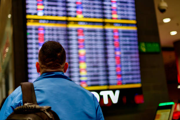 Passenger checks his flight in front of the arrivals and departures screen at El Dorado airport stock photo