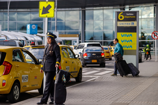 Bogota, Colombia - January 23, 2023: Female pilot waits for a cab at the entrance of El Dorado airport