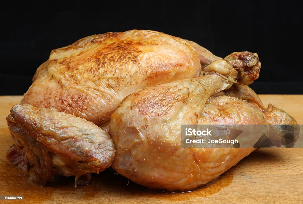 Roast Chicken Freshly roasted chicken on wooden carving board Black Background Stock Photo