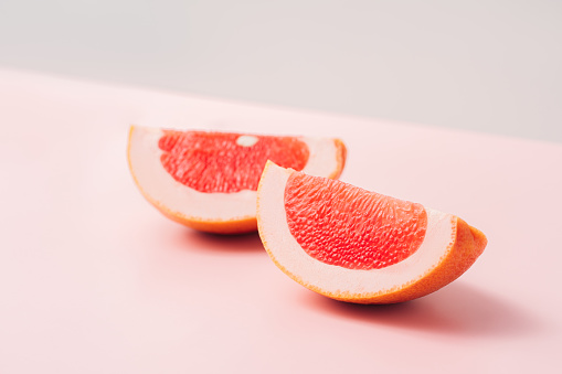 Two grapefruit slices against a green-pink background.