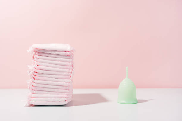 istock Menstrual cup next to pack of pads on white table against pink background 1468069513