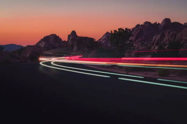 Light trails from cars driving through Joshua Tree National Park at sunset.