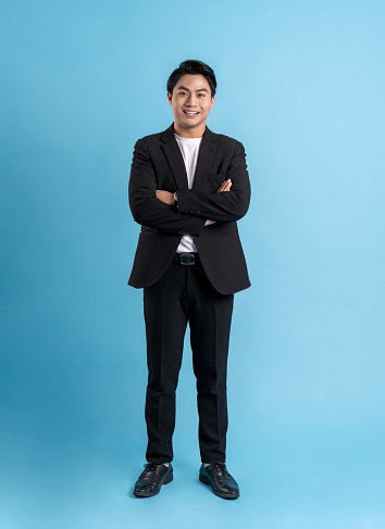 Full body Young business man wearing a vest posing on a blue background