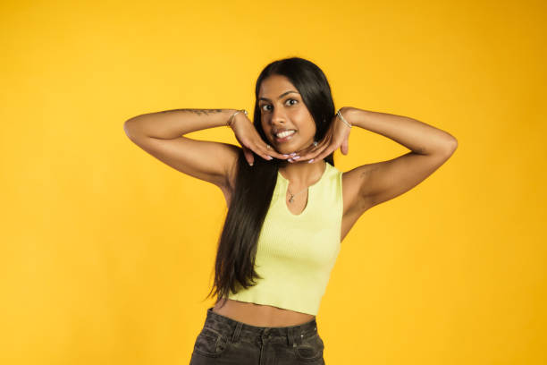 Woman posing with her long hair against the yellow background.