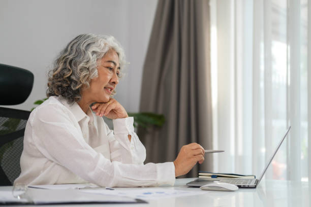 istock Senior businesswoman doing paperwork, signing contracts, documents while working on laptop in her office. 1468090436