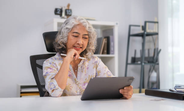 istock Elegant middle aged businesswoman with a natural friendly smile using digital tablet at office. 1468090475
