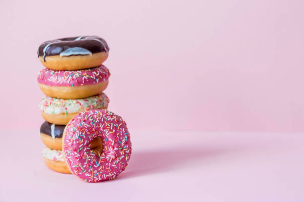 istock Delicious dessert. Pink, white and chocolate donuts with multicolored sprinkles on a pink background of Sweets. Confectionery products. 1468090980