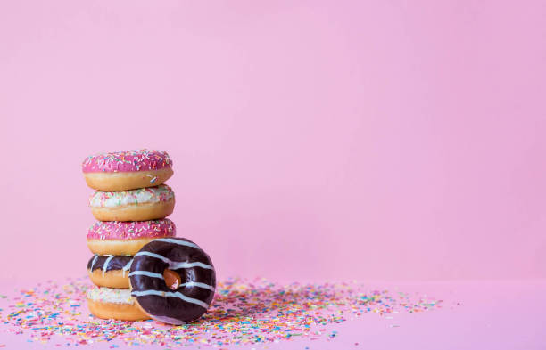 istock Delicious dessert. Pink, white and chocolate donuts with multicolored sprinkles on a pink background of Sweets. Confectionery products. 1468090991