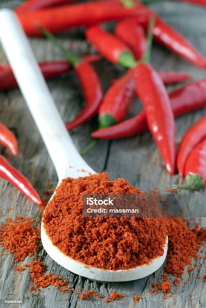 chilli powder close up of spoon heaped with chilli powder with red chillies in background Cayenne Pepper Stock Photo