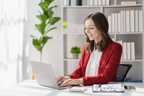istock American businesswoman smiling confidently using laptop computer working on financial statistics presentation with graph document Female accountant analyzing data in office looking at camera 1468094526