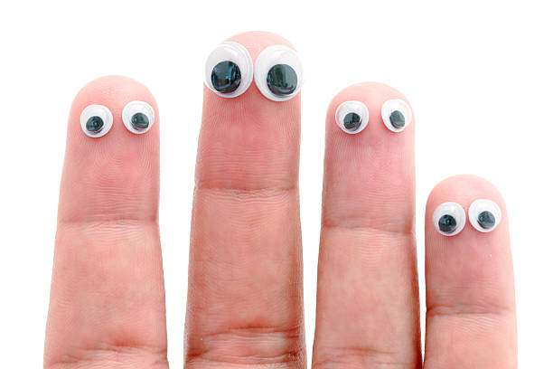 Sticky wiggle eyes stuck on four fingers isolated against a white background.