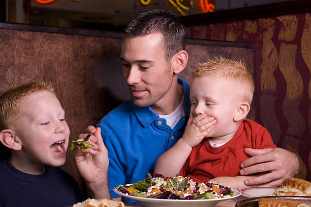 istock dad and sons sharing salad at a restaurant 146809567