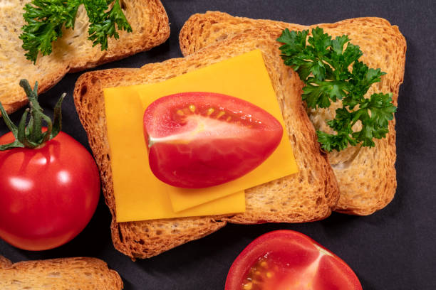 Four Biscotti Crackers, Cheddar Cheese, Tomatoes and Curly Parsley on Black Background