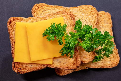 Three Biscotti Crackers, Cheddar Cheese and Curly Parsley on Black Background