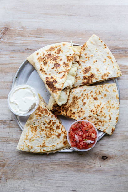 istock Chicken quesadilla cut in four pieces and served on a silver plate on a wooden table. 1468112164
