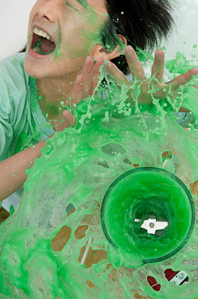 Asian boy laughing hysterically being slimed by overflowing blender Asian boy laughing hysterically being slimed by out of control green fluid from overflowing blender child laughing hysterically stock pictures, royalty-free photos & images