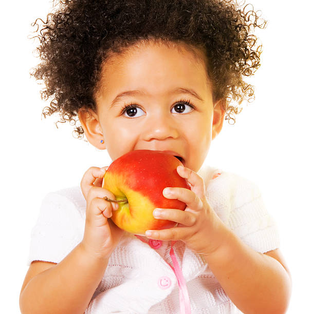 Portrait of a pretty little girl biting an apple