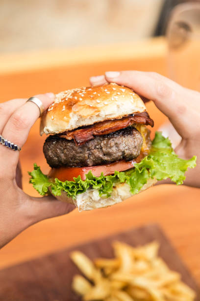 istock Hands holding a burger, on a restaurant table. Delicious and nutritious food. 1468117941