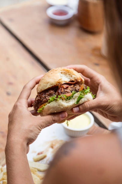 istock Hands holding a burger, on a restaurant table. Delicious and nutritious food. 1468117968