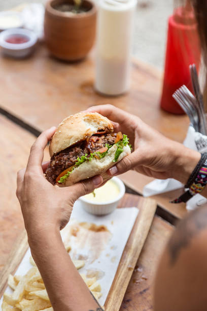 istock Hands holding a burger, on a restaurant table. Delicious and nutritious food. 1468118032
