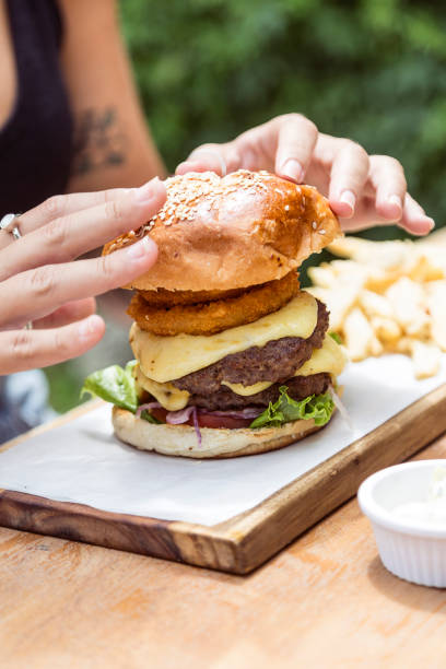 Hand holding a whole hamburger, on a restaurant table. Delicious and nutritious food.