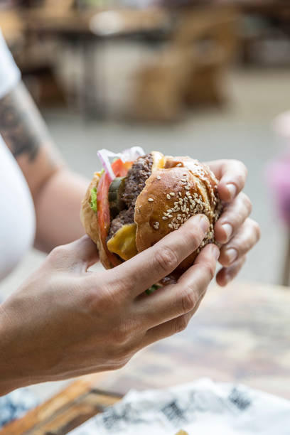 istock Hands holding a burger, on a restaurant table. Delicious and nutritious food. 1468118113