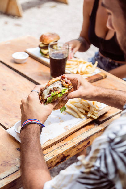 Hands holding a burger, on a restaurant table. Delicious and nutritious food.