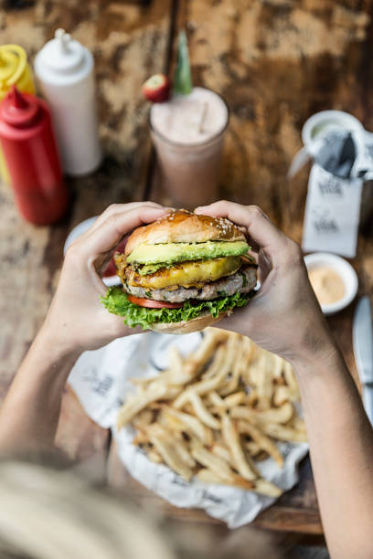 Hand holding a chicken burger, at a restaurant table. Delicious and nutritious food.