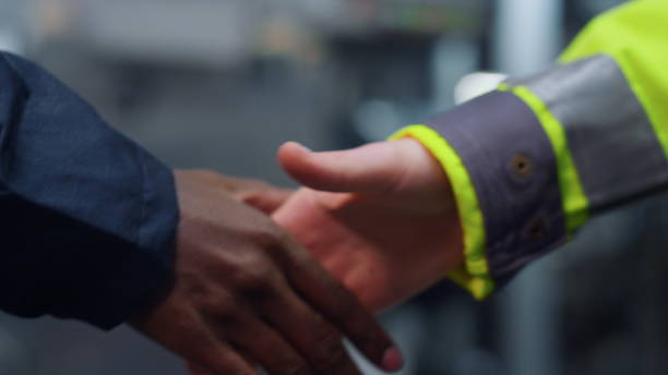 Happy Latin American business owner greeting an employee with a handshake at an industrial bakery