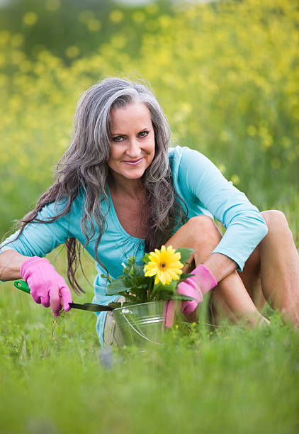 mulher jardinagem em campo de flores silvestres - planting clothing gray hair human age - fotografias e filmes do acervo