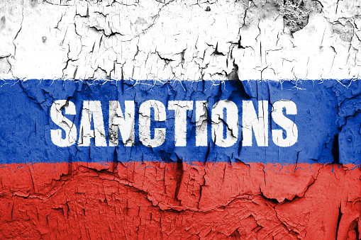 Flag of Russia painted on a wall with word SANCTIONS. Embargo and sanctions for military aggression.
