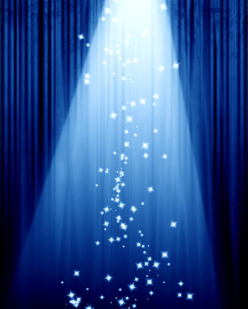 Blue curtain in a theater and a spotlight with sparkles stock photo