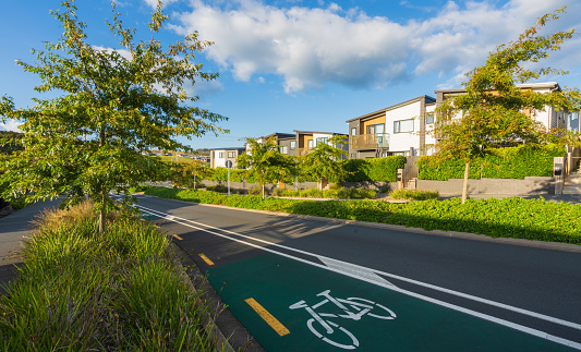 View of modern townhouses in row in blue sky with cycle lane in front.