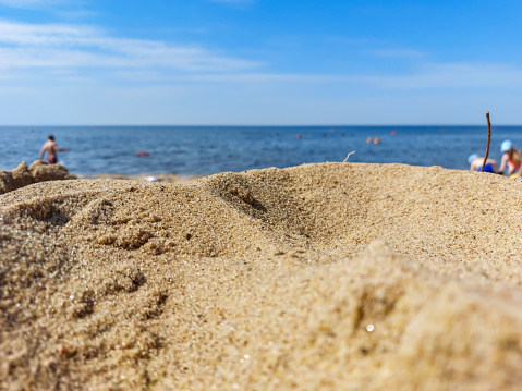 Yellow, fine sand on sunny Baltic sea beach with blue water and bright sky in the background in summer. Sand grains in sunlight. Beach scenery