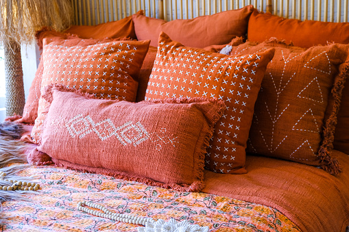 Closeup of headboard in bedroom in staging model home, house or apartment with decorative bright coral pillows. Home interior with natural materials pillow cases