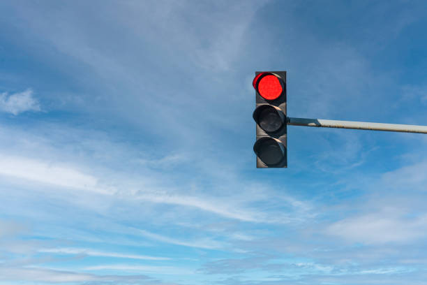 Modern traffic light with red light in front of cloudless sunny blue sky Modern traffic light with red light in front of cloudless sunny blue sky stoplight stock pictures, royalty-free photos & images