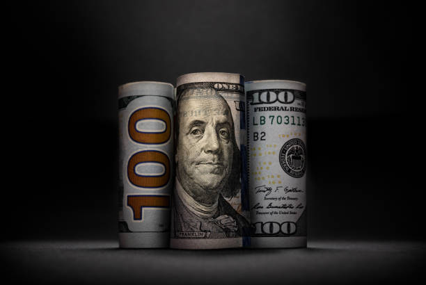 istock Three different images of 100 US dollars in rolls on dark background 1468130663
