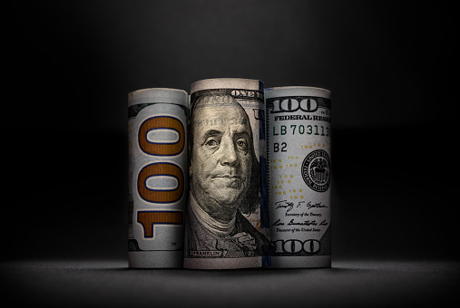 Three different images of 100 US dollars in rolls on dark background