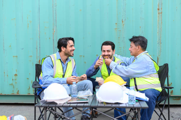 istock Group of logistic staff workers talk and rest sitting in the shipping yard container during break time. Cargo ship import export factory logistic transport and global business concept. 1468132155