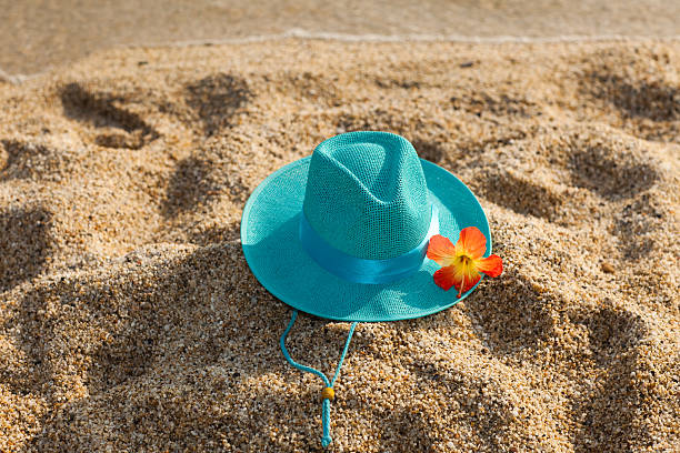 Turquoise summer hat and flower on the beach stock photo