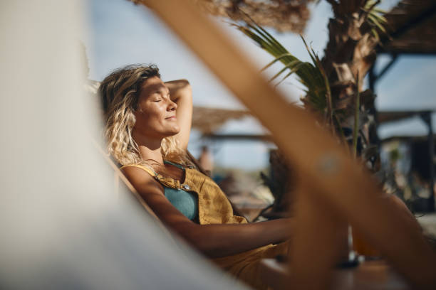 istock Smiling woman relaxing on a deck chair at the beach. 1468134178