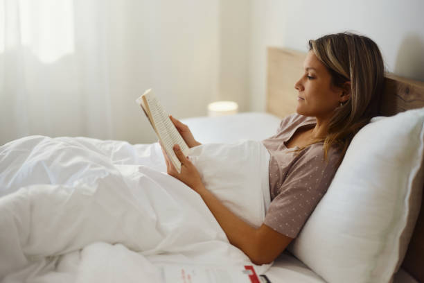istock Relaxed woman reading a book in a bed. 1468136856