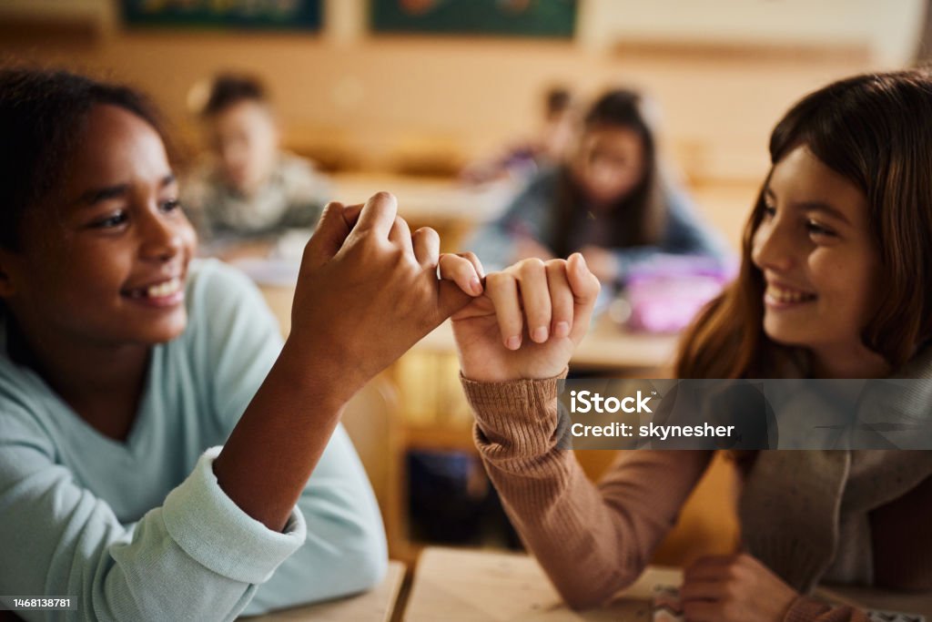 Reconciliation at school! Close up of happy schoolgirls reconciling with little fingers at school. Child Stock Photo
