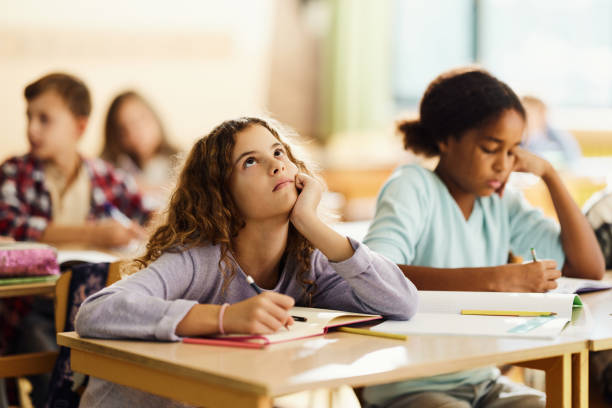 小学校のクラスで書く退屈な女子高生。 - learning boredom studying child ストックフォトと画像