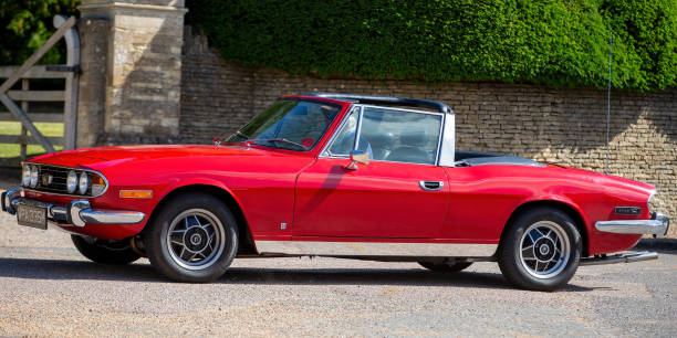 Turvey, Bedfordshire, UK - June 12th 2022. 1974 red Triumph Stag driving through an English village